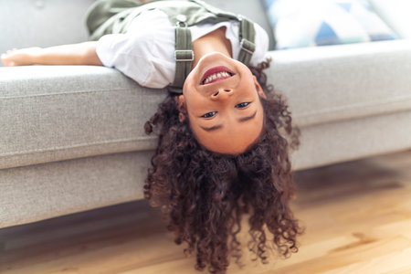 Little girl kid with very long beautiful hair upside down on sofa.の写真素材