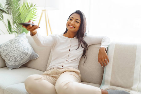 Portrait of a young woman using a control remote at home.