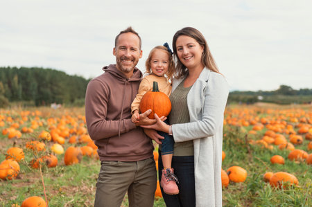 family and daughter on a field with pumpkins