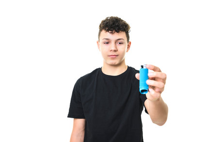 teen boy using asthma inhaler on white background