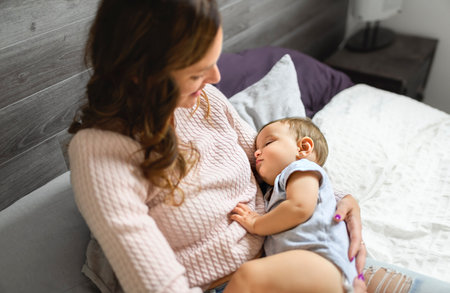 Young woman breastfeeding her baby at homeの写真素材