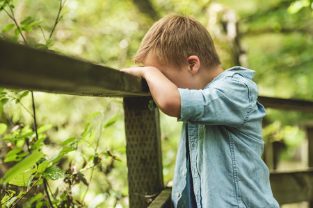 Portrait of a sad boy with down syndrome in a park
