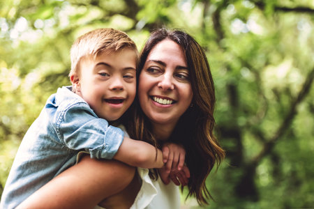 Portrait of a little boy with down syndrome while playing in a park with his mother