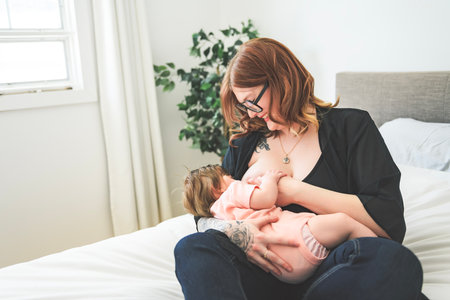 Soft photo young mother feeding breast her baby at home in bed roomの写真素材