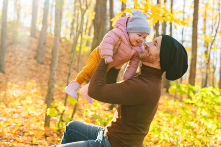 Baby daughter and her father in the autumn season in parkの写真素材