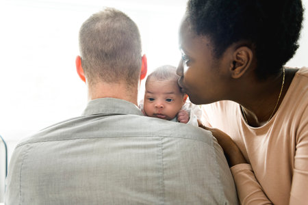 A Portrait of a beautiful family, with her nursing baby on bedroom close to a window