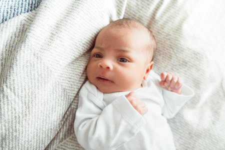 black newborn baby lay on bed at home