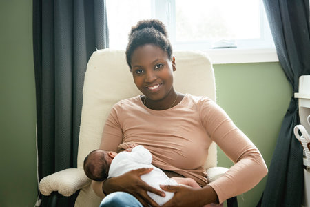 A black woman breast feeding her child girl at homeの写真素材