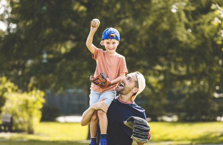 Father and son playing baseball in sunny day at public parkの写真素材