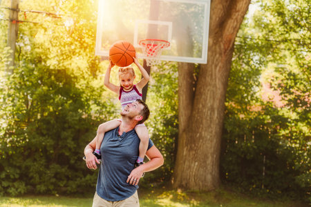 Happy father and child daughter outside at basketball court.