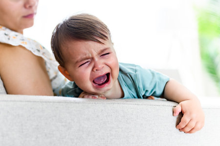 mother holding child baby on the living room. The baby is sick having some cough