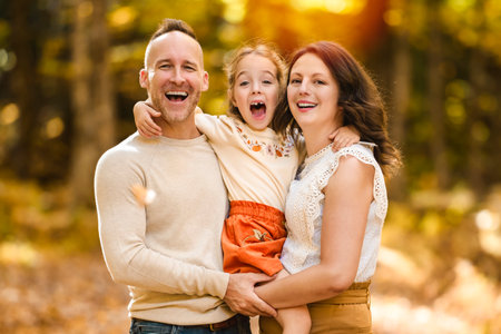 Mature family with daughter on a walk in autumn forest.の写真素材