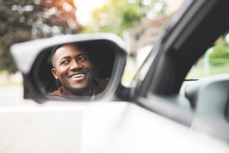 young black man with his new car look on mirror