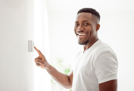 A smiling man adjusting thermostat on home heating system