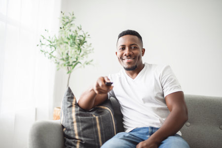 Man wearing white shirt on sofa using remote control