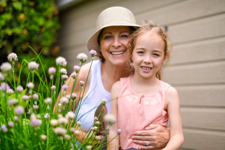 grandmother and granddaughter digging soil with gardening tools in yardの写真素材