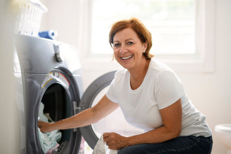 senior Woman Doing Laundry near a Washing Machineの写真素材
