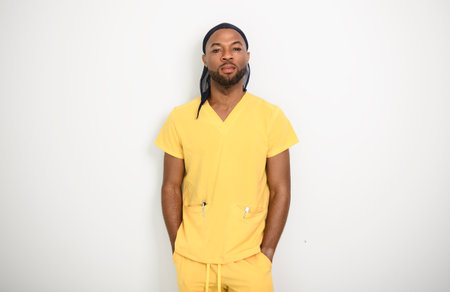 Portrait of a friendly black male nurse wearing yellow scrubs uniformの写真素材
