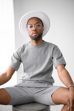 Portrait of black fashion man wearing great looking clothes with white hat