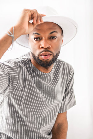 Portrait of black man wearing great looking clothes with white hat