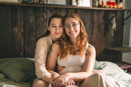 Happy couple cuddling on their bed at home. Romantic young LGBTQの写真素材