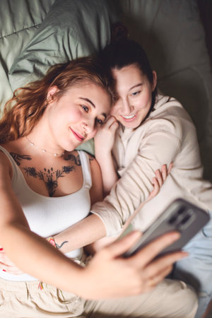 Happy couple cuddling on their bed at home. Romantic young LGBTQ