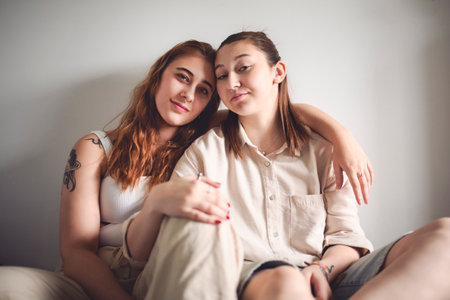 Happy couple cuddling on their bed at home. Romantic young LGBTQの写真素材