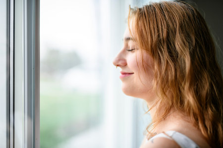 beautiful young woman in the bedroom close to a window