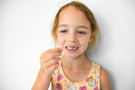 Smiling little girl missing tooth on white background