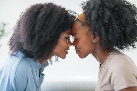 Affectionate mother and daughter sitting on sofa at homeの写真素材