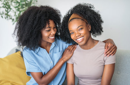 Affectionate mother and daughter sitting on sofa at homeの写真素材