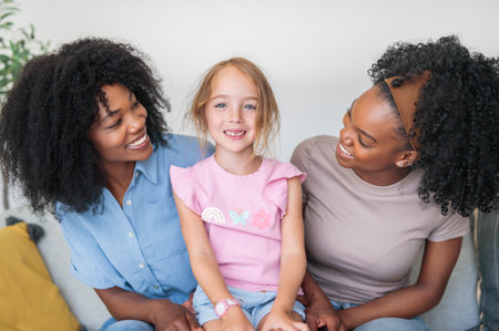 A affectionate mother and daughter sitting on sofa at home with little girlの写真素材