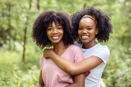Black American mother and her daughter in forest.
