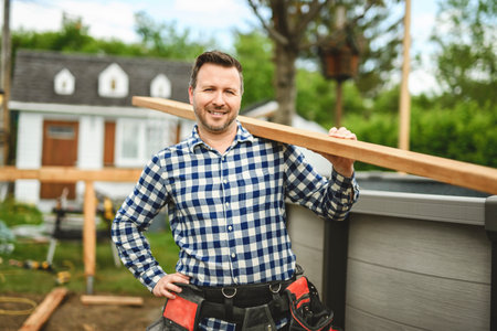 Handyman worker making patio outside close to a pool holding wood