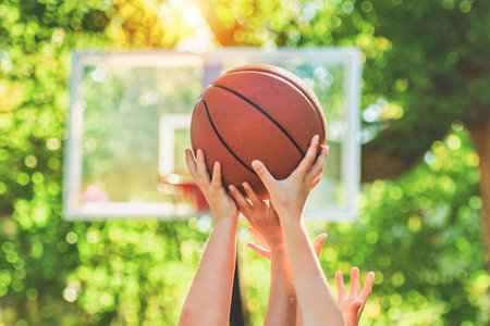 lot of hands holding basketball on courtの写真素材