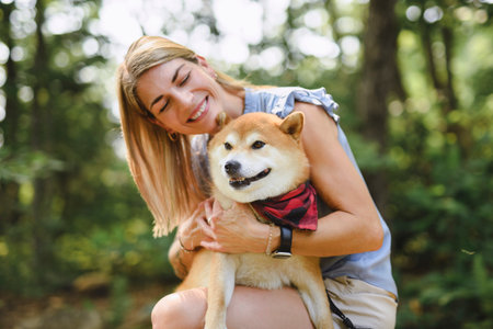 Happy woman with her Shiba Inu dog in the forest on summer seasonの写真素材