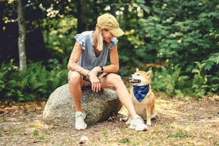 Happy woman with her Shiba Inu dog in the forest on summer seasonの写真素材