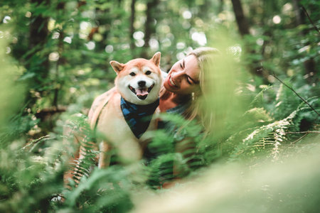 Happy woman with her Shiba Inu dog in the forest on summer seasonの写真素材