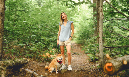 Happy woman with her Shiba Inu dog in the forest on summer season