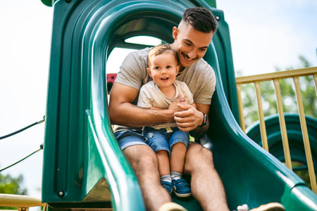 father with child boy is sitting on the slide with itの写真素材