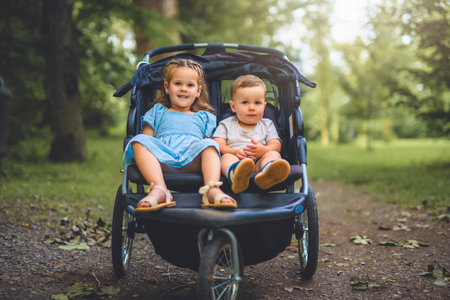 two child sit on stroller on forest