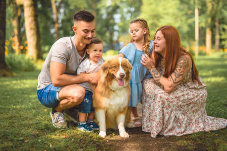Beautiful happy family enjoying in the park with his australian shepherd dogの写真素材