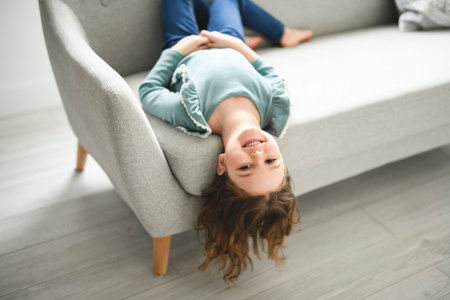 Portrait of a cute 6 or 7 years old girl on sofa at homeの写真素材