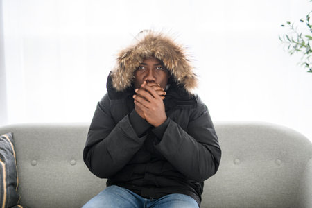Unwell man sit in cold living room suffer from heat lack.