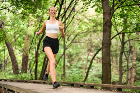 Happy athletic woman running while exercising in nature. Copy space.