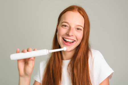A cheerful woman happily enjoys her morning routine while brushing her teeth in a bright, sunny bathroomの写真素材