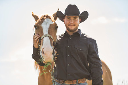 cowboy, stands next to her horse in summer seasonの写真素材