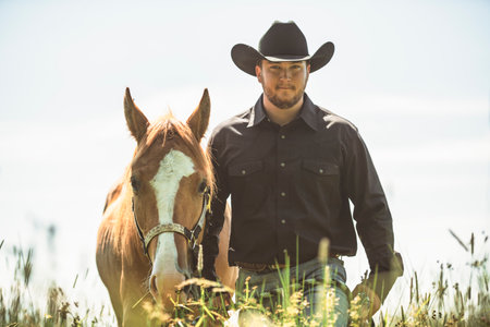 cowboy, stands next to her horse in summer seasonの写真素材