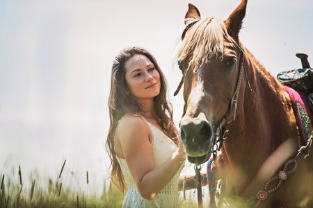 woman cowgirl, stands next to her horse in summer seasonの写真素材