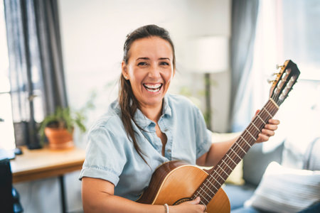 woman playing guitar at home living roomの写真素材